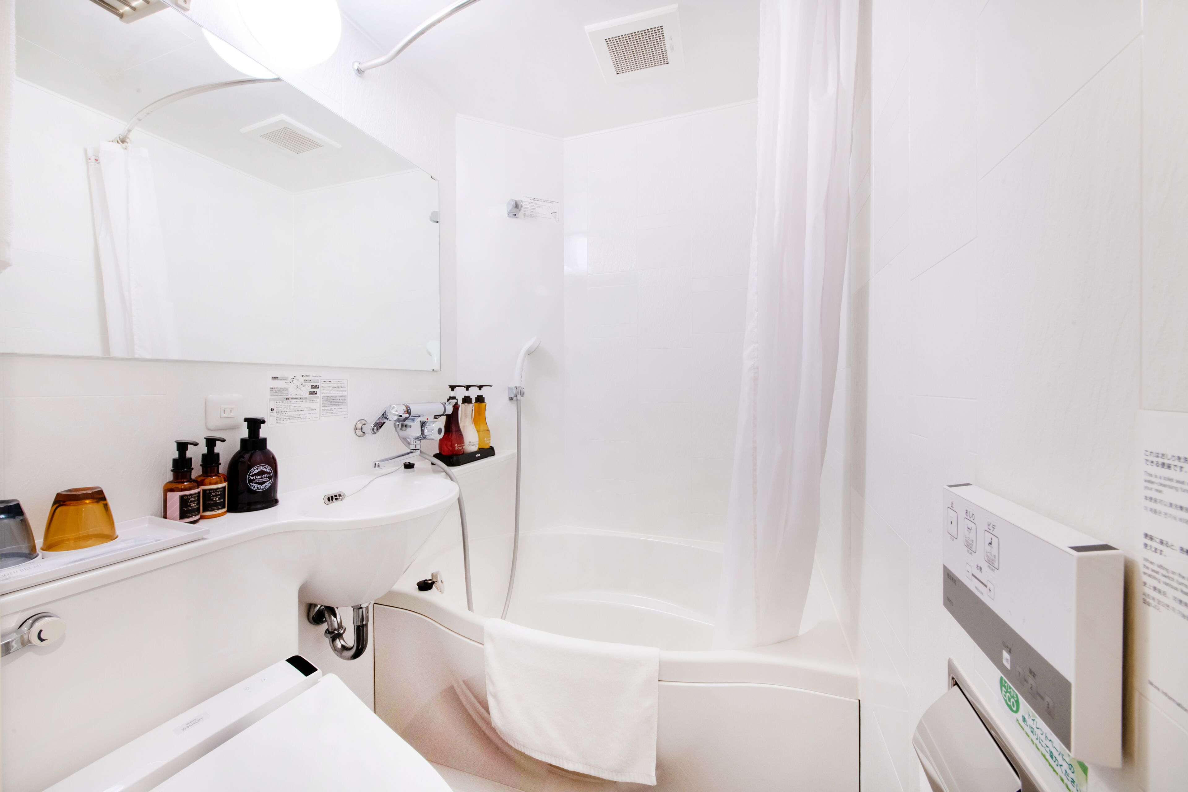 A modern bathroom with a white sink, mirror, and shower area.