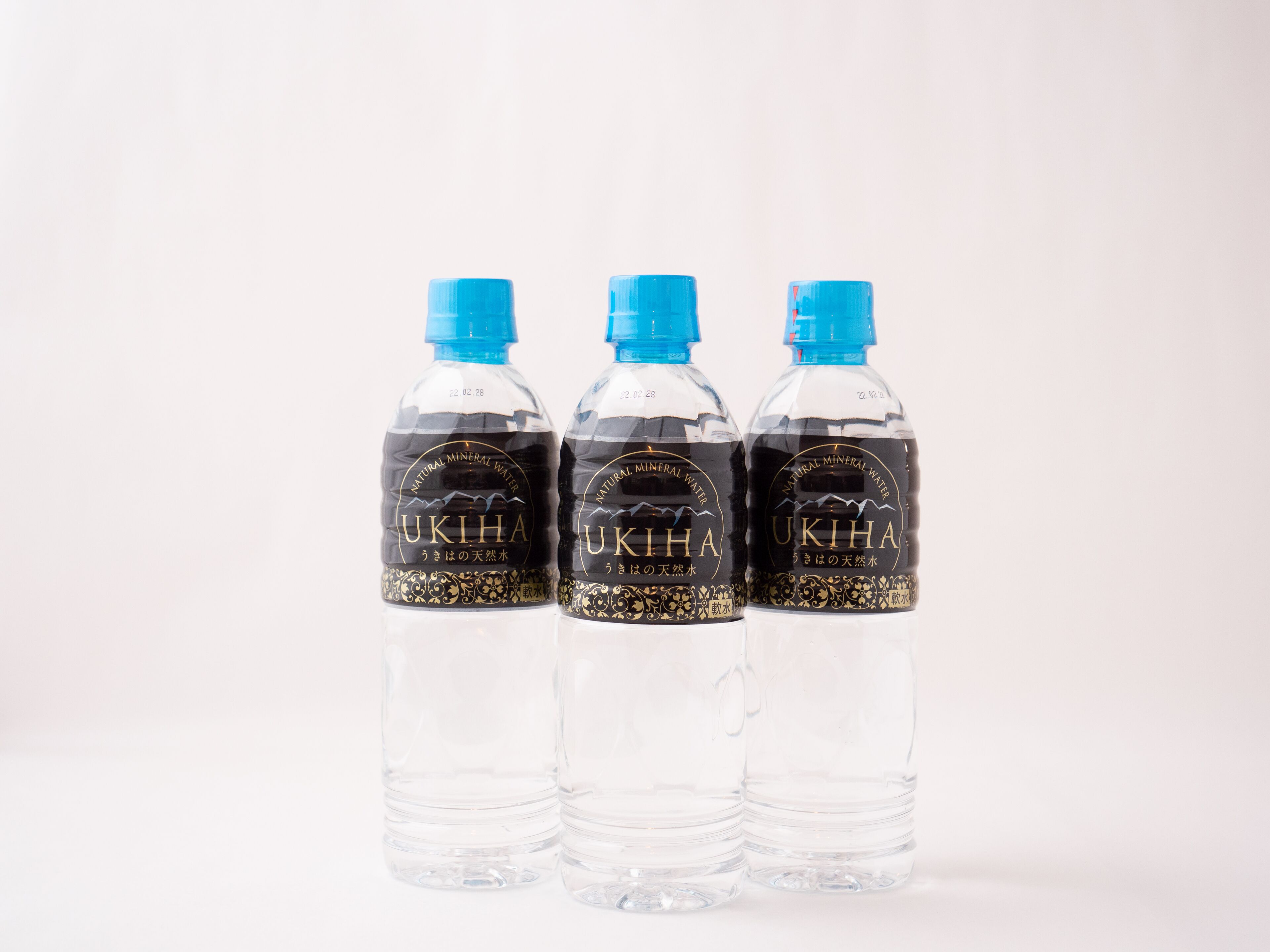 Tres botellas de plástico transparente con tapas azules, etiquetadas como "UKIHA" y "Agua Mineral Natural".