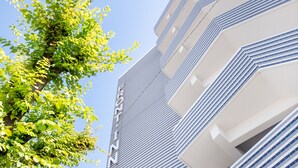 Un bâtiment moderne à la façade géométrique, avec un arbre au premier plan.