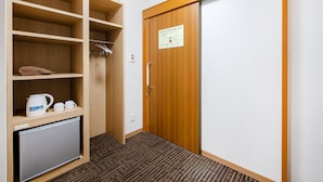 Une chambre d’hôtel avec une armoire en bois, un petit réfrigérateur et une machine à café.