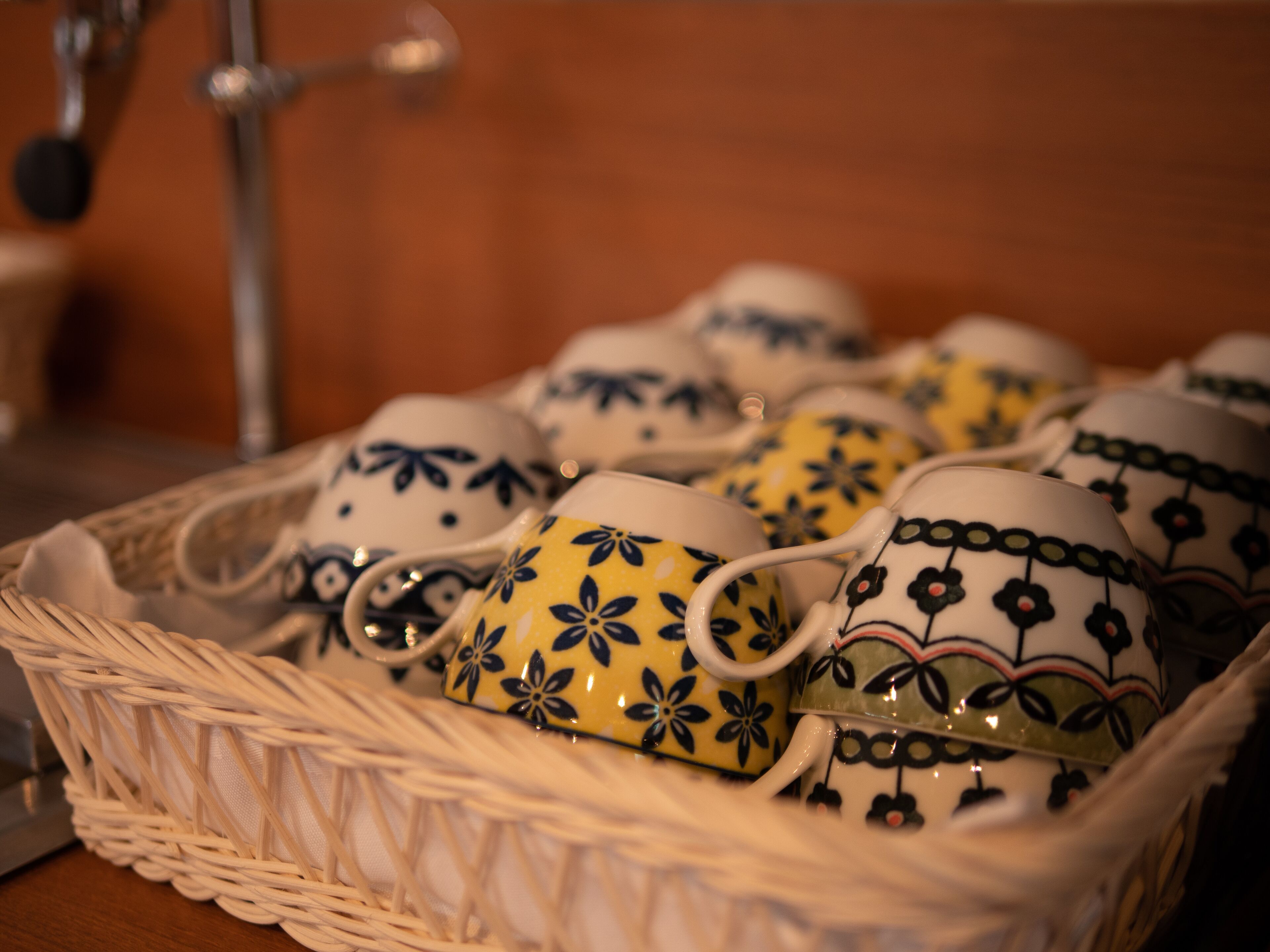 A basket containing several ceramic cups with floral patterns.