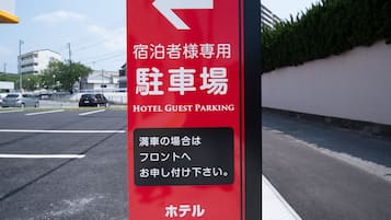 A hotel guest parking sign with directional arrows and text indicating the parking area is for hotel guests only.
