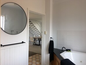 A bathroom with a round mirror, a black towel, a sink, and a tiled floor. - Lakehouse At Mulwala - Two jetties and private boat ramp (Mulwala)