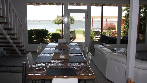 A dining area with a view of the water, a staircase, and a white sofa.