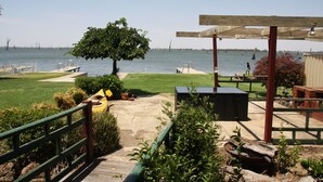 A patio area with a view of the water, a wooden deck, and a covered seating area.