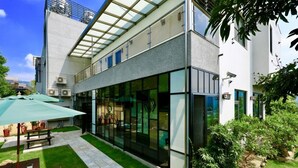 A modern building with large glass windows, a covered outdoor seating area, and a well-maintained lawn. - Five mountains and Three Water B&B (Shuili)
