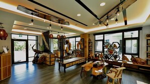 A spacious room with a wooden floor, a staircase, and a seating area with a bench and chairs. - Five mountains and Three Water B&B (Shuili)