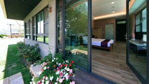 A modern hotel room with a large glass wall, a wooden floor, and a bed with a purple blanket. - Five mountains and Three Water B&B (Shuili)