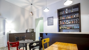 Eine moderne Küche mit einem Holztisch und Stühlen, einer Bar mit Regalen voller Flaschen und einem Schild mit Küchenutensilien.