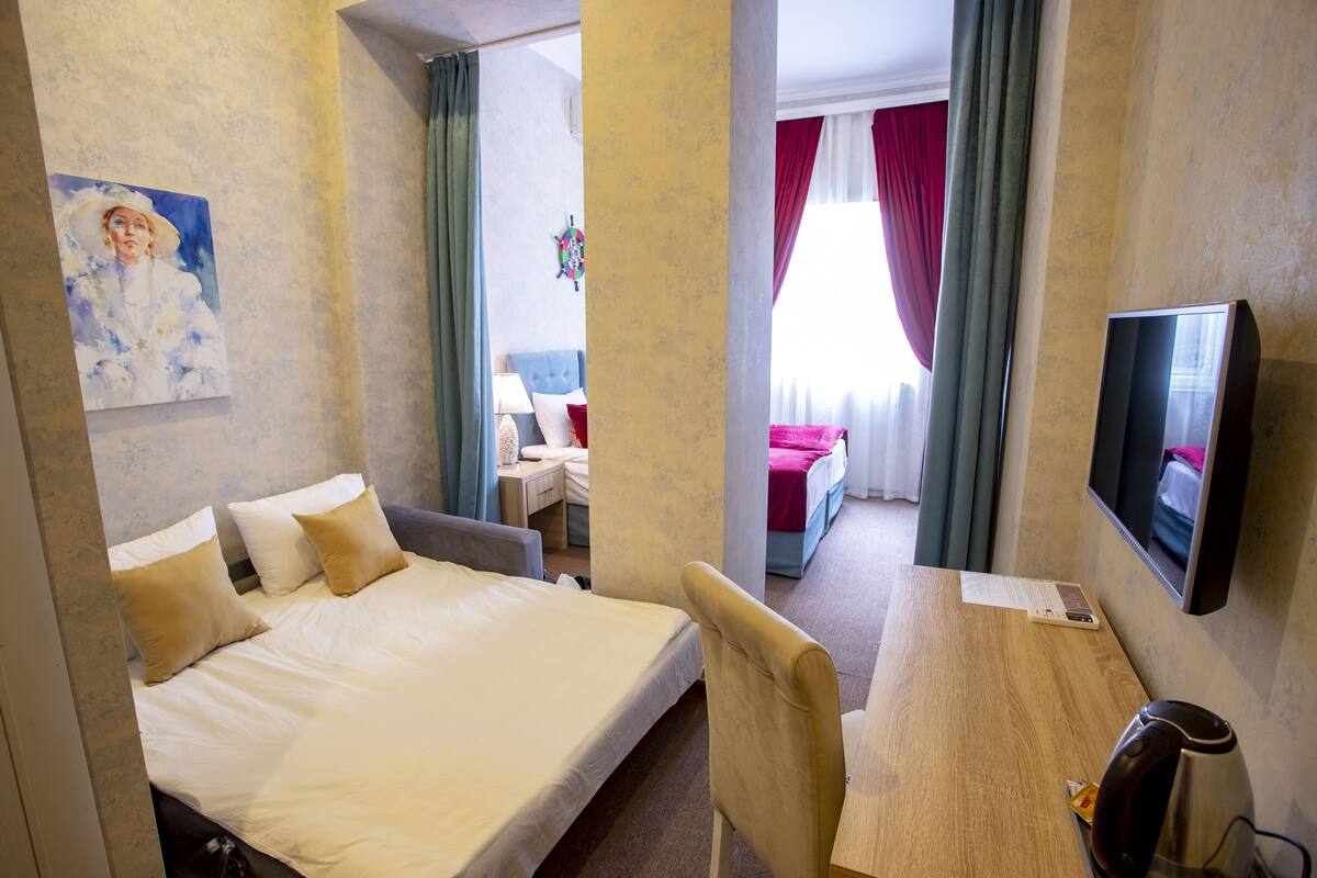 Une chambre d’hôtel avec un lit, un bureau, une chaise, une télévision et un tableau au mur.