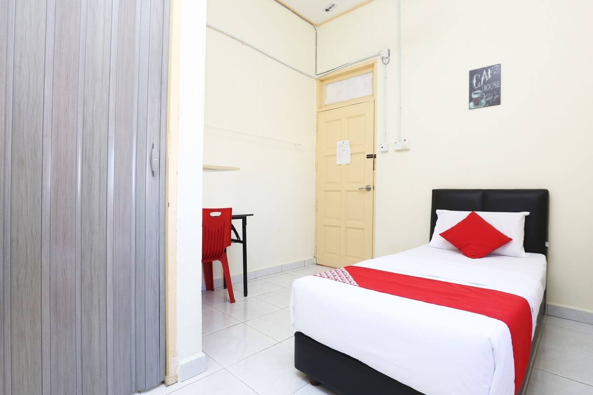 Una habitación de hotel con una cama, una silla roja, una mesita y una puerta.