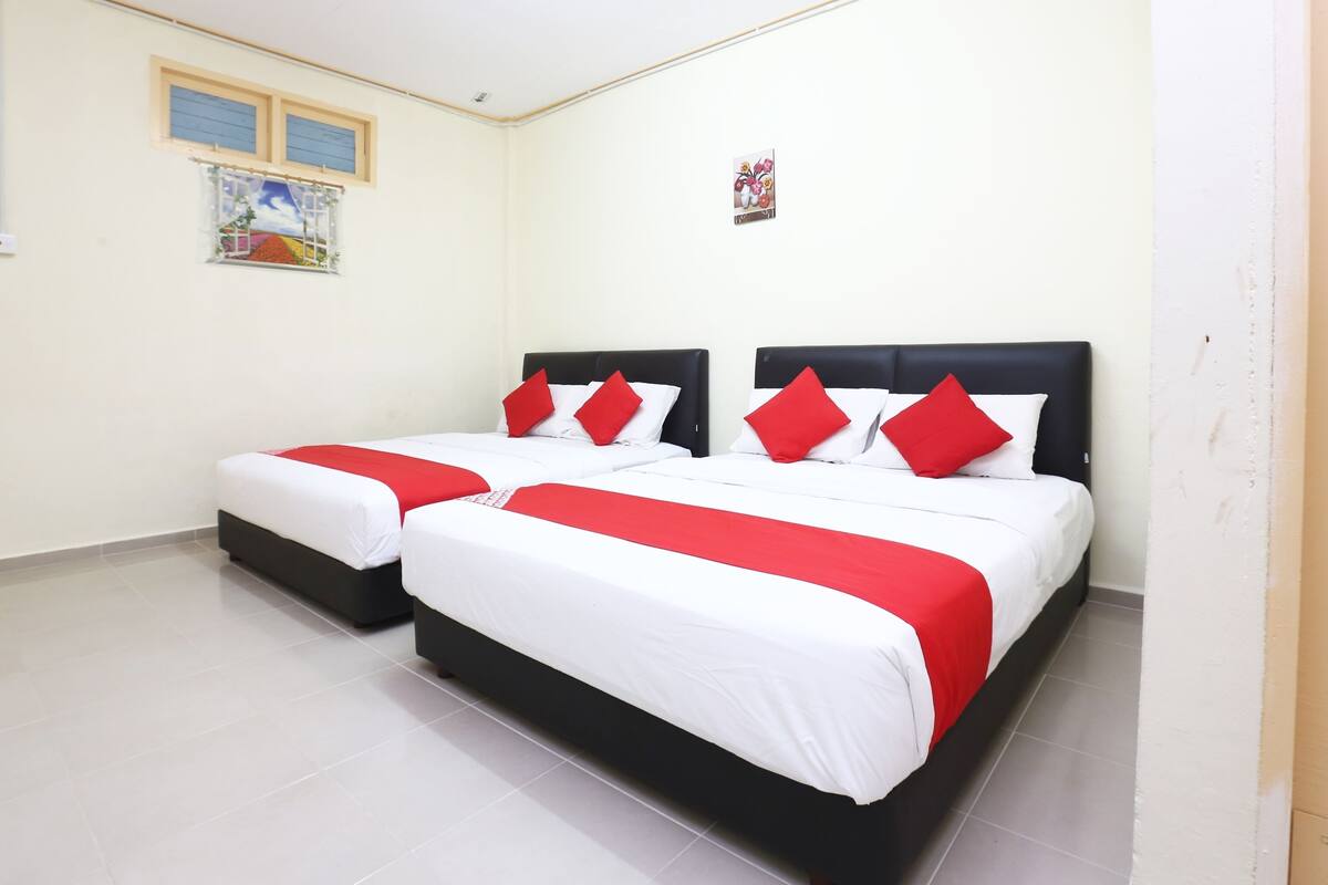 Habitación de hotel con dos camas, cada una con cabecero negro y ropa de cama blanca.