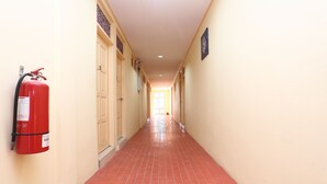 Un passadís amb un extintor a l'esquerra, portes als dos costats i un senyal a la paret dreta.