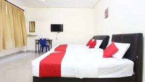 Habitació d'hotel amb un llit gran, escriptori, cadira, televisió i ventilador de sostre.