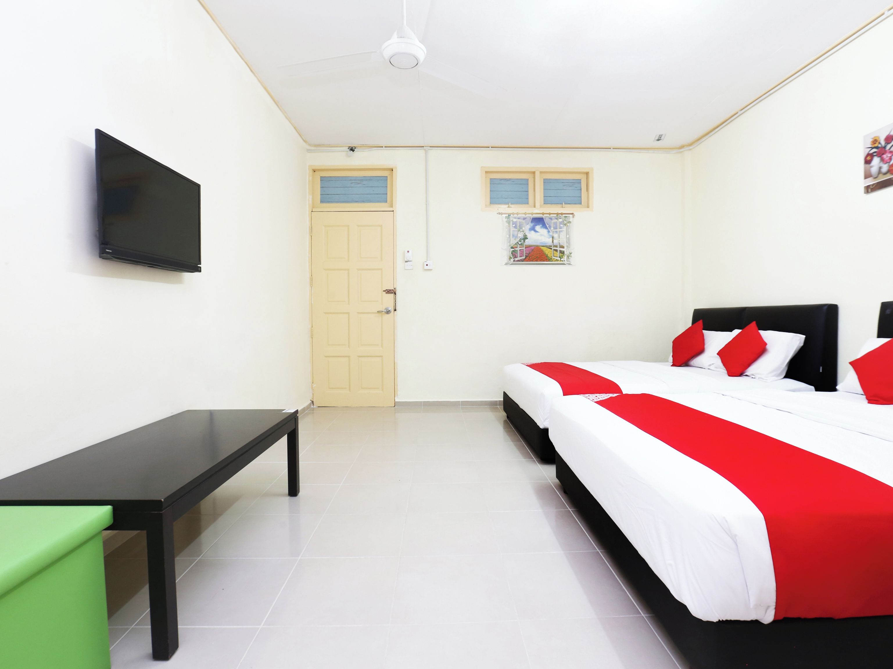 A hotel room with a bed, a desk, a television, and a door.