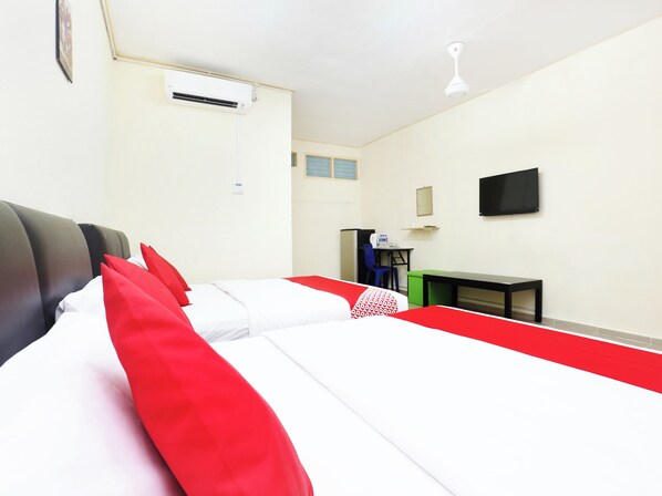 Una habitación de hotel con cama, escritorio, silla, televisor y aire acondicionado.