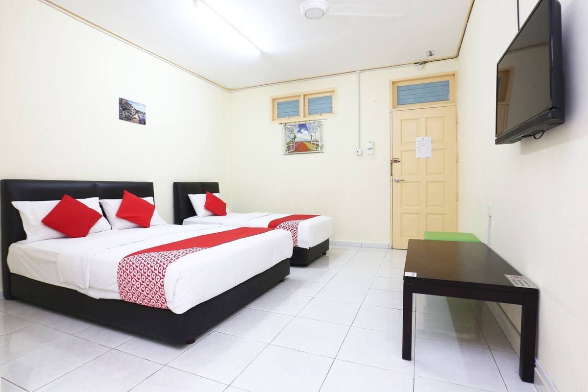 Habitación de hotel con dos camas, un escritorio, un televisor y una puerta.