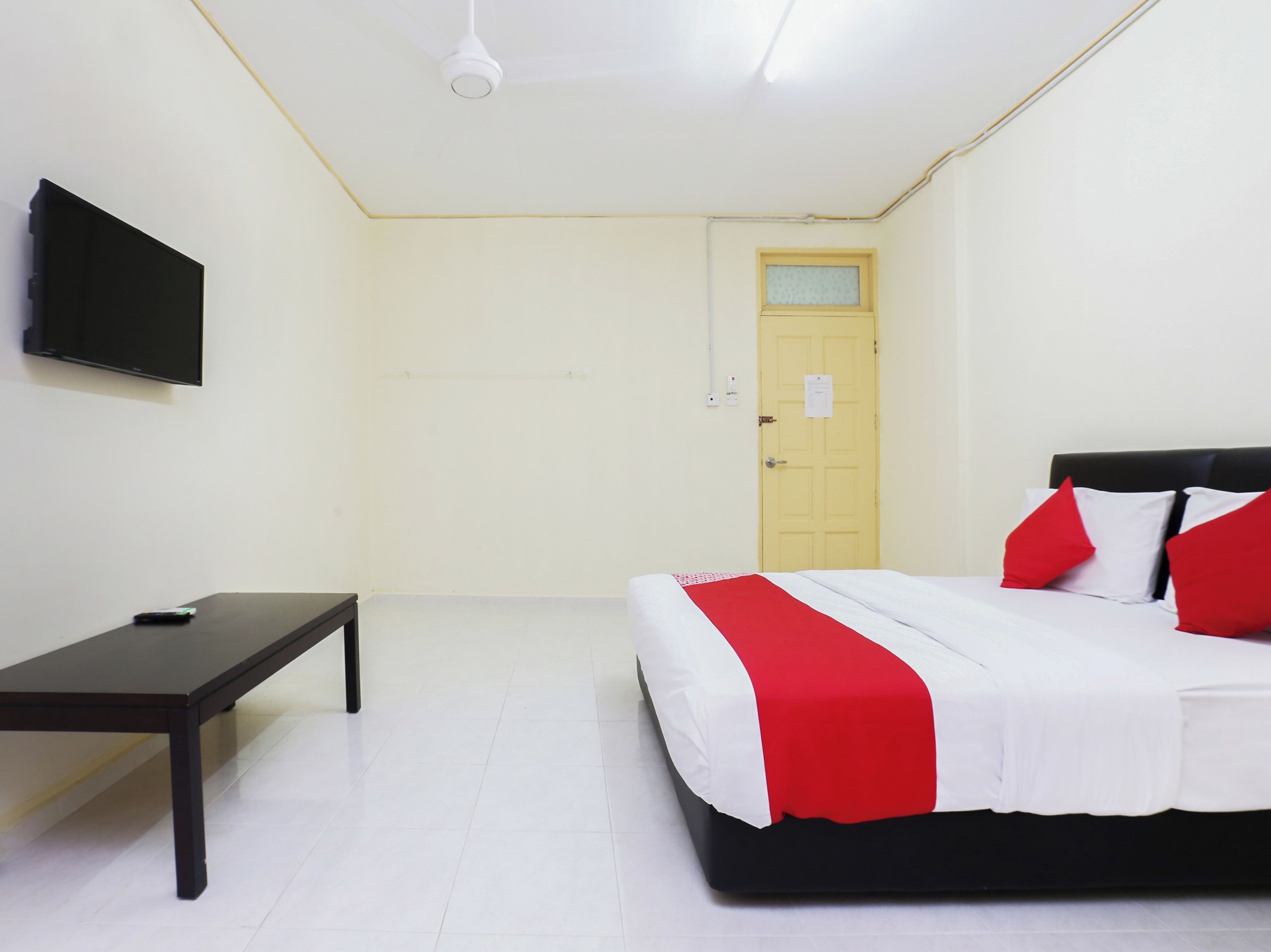 A room with a bed, a desk, a television, and a door.