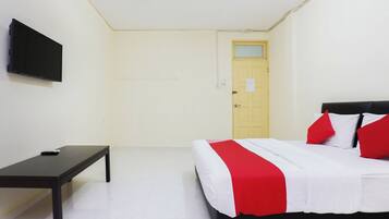 A room with a bed, a desk, a television, and a door.