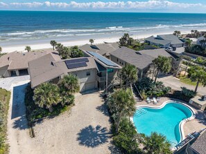 A residential area with a swimming pool, beach, and ocean view.