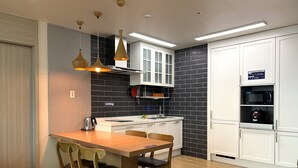 Une cuisine moderne avec une table à manger en bois, des chaises et des luminaires suspendus.