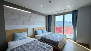 Une chambre d’hôtel moderne avec deux lits, une grande fenêtre avec des rideaux et une vue sur les montagnes.