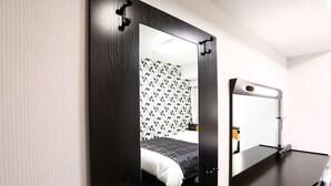 Una habitación de hotel compacta con cama, escritorio y espejo.