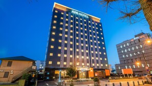 Un hotel de varios pisos con un llamativo letrero que dice 'APA HOTEL' en la parte superior.
