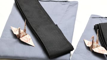 A neatly folded grey fabric with a black edge and a decorative paper crane.