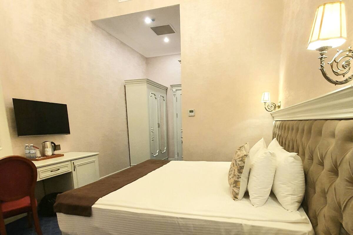 Ein Hotelzimmer mit Bett, Schreibtisch, Stuhl, Fernseher und Kleiderschrank.