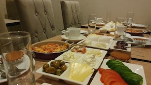 A dining table set with various dishes, including eggs, cheese, ham, olives, and vegetables. - La Casa Sahil Hotel (Baku)