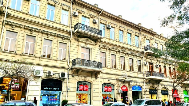A multi-story building with various shops on the ground floor, including a restaurant and a boutique. - La Casa Sahil Hotel (Baku)