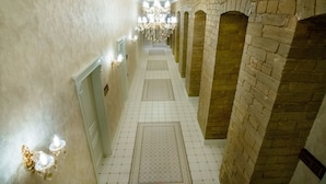 A corridor with a tiled floor, a chandelier, and brick walls. - La Casa Sahil Hotel (Baku)
