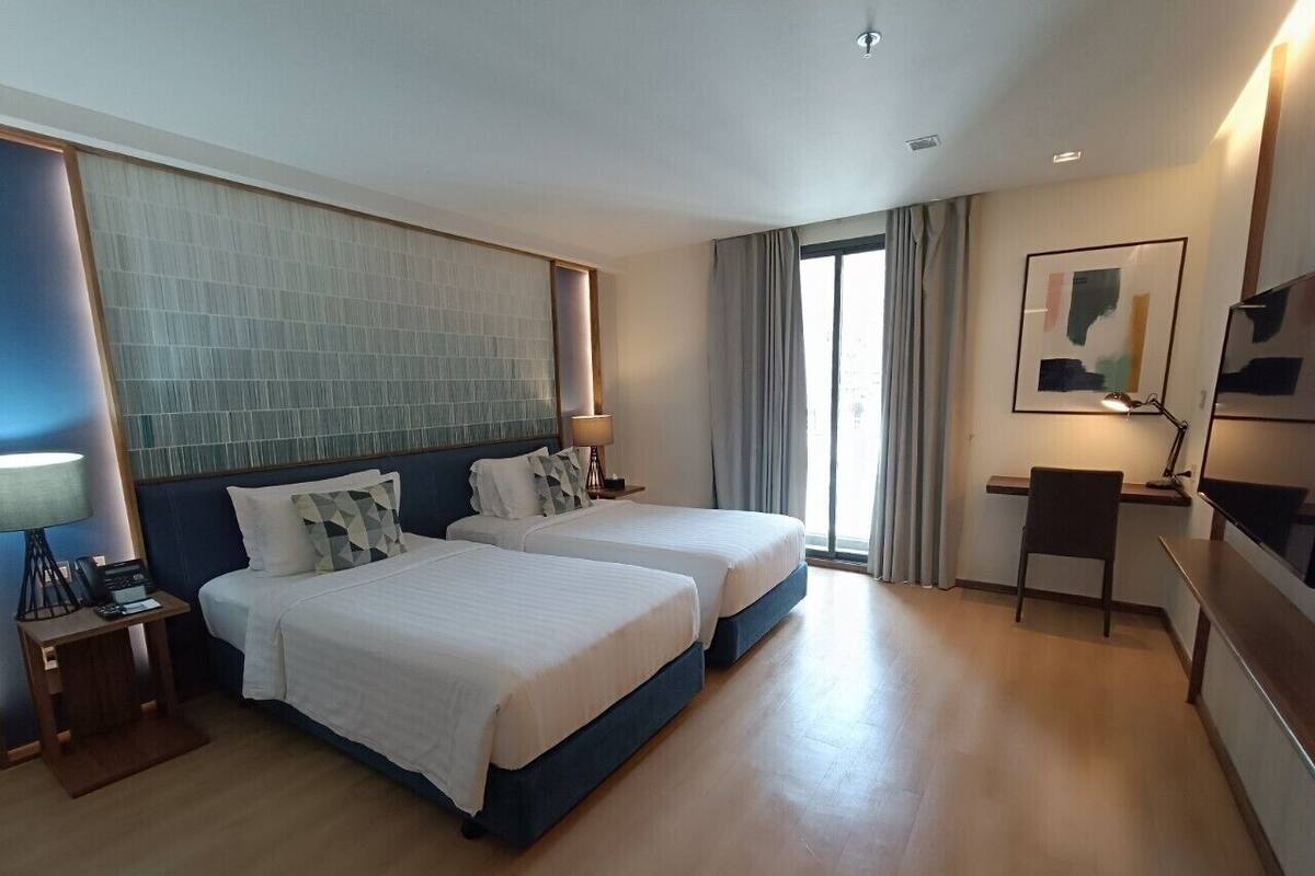 A hotel room with two beds, a desk, and a chair.