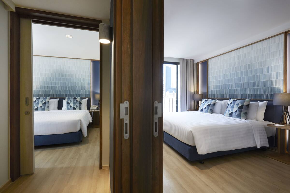 A hotel room with two beds, a large window, and a view of the city.