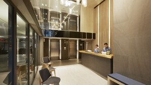 A modern hotel lobby with a reception desk, seating area, and elevators. - The Quarter Phromphong by UHG (Bangkok)
