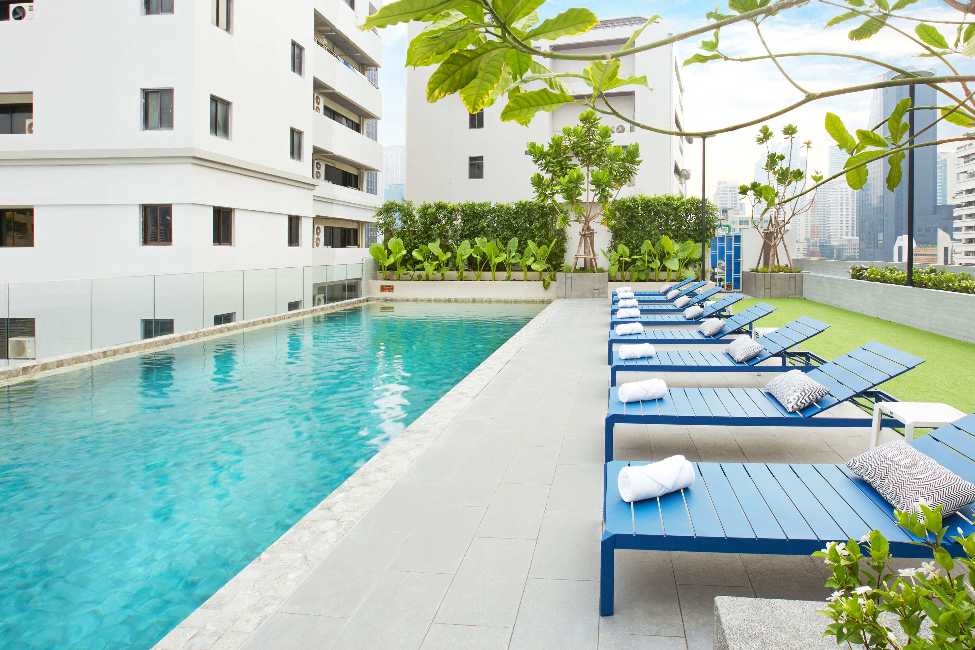 A swimming pool with blue lounge chairs and a white building in the background.
