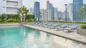 A rooftop pool with lounge chairs, a city skyline in the background, and modern buildings. - The Quarter Phromphong by UHG (Bangkok)