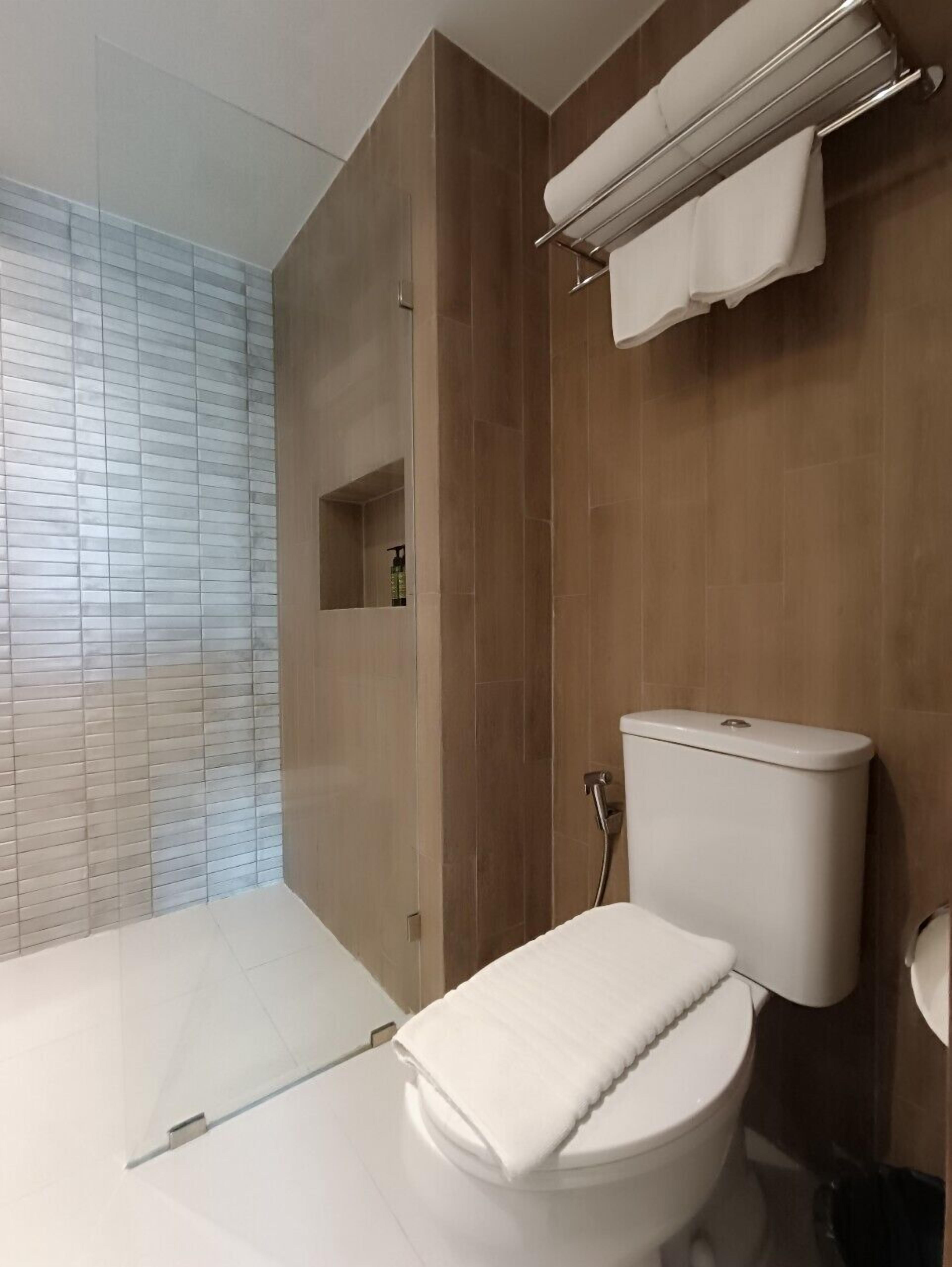 A modern bathroom with a shower, toilet, and a towel rack.