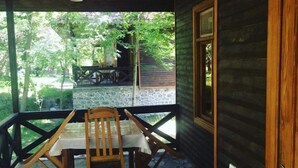 A wooden cabin with a stone floor and a wooden table with chairs.