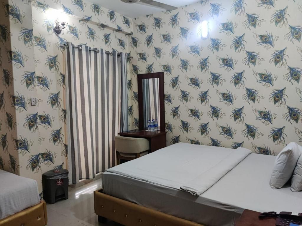 A hotel room with a bed, a desk, a chair, a mirror, and a curtain.