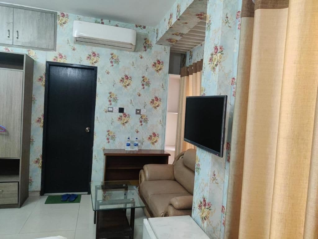 Een woonkamer met een bank, een televisie, een glazen salontafel, een kledingkast en een deur.
