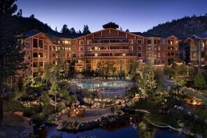 Ein großes Chalet mit mehreren Etagen, einem zentralen Innenhof mit Pool und einer Bergkulisse.