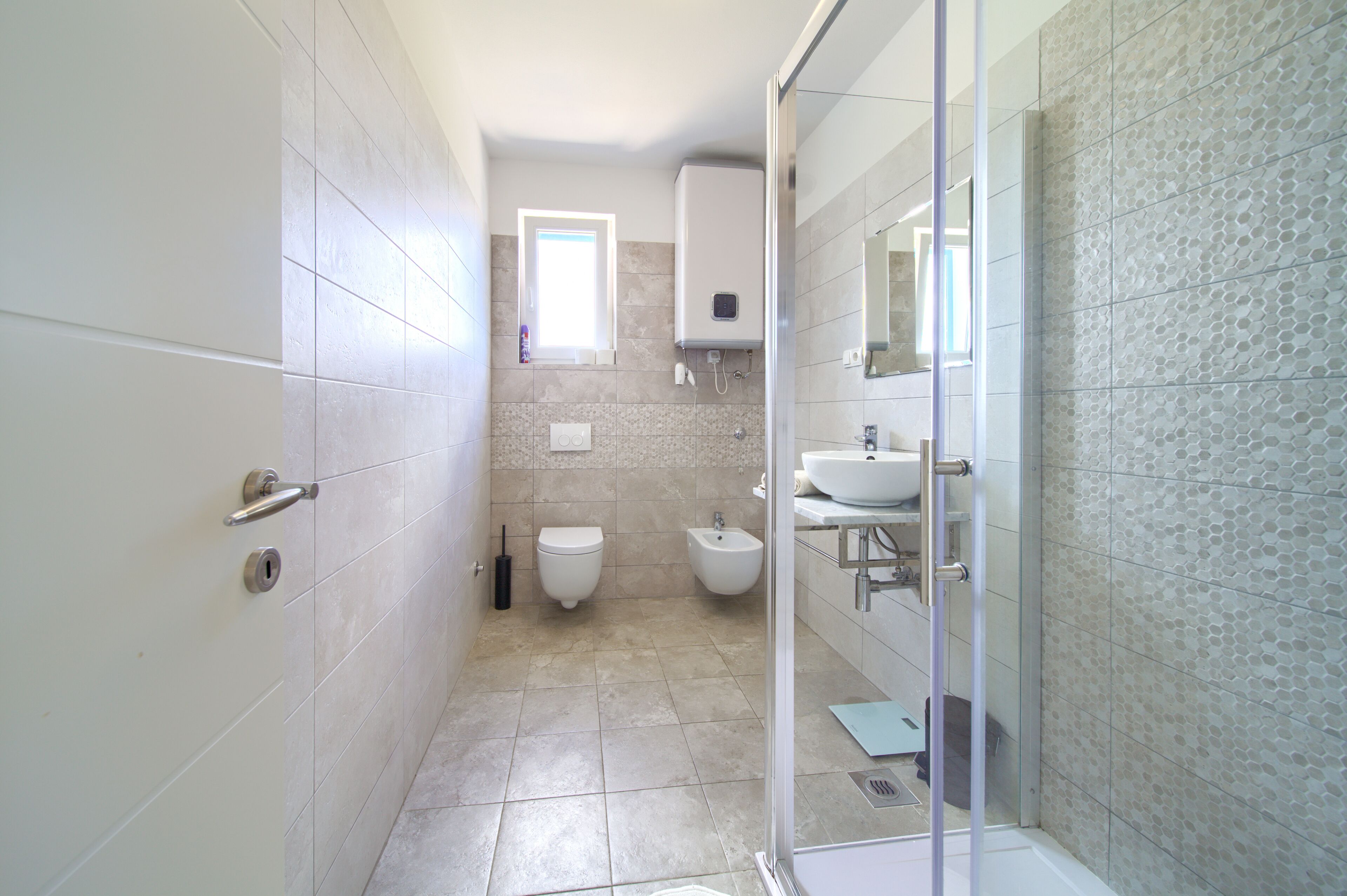 Ein modernes Badezimmer mit Toilette, Bidet und einer Duschkabine aus Glas.
