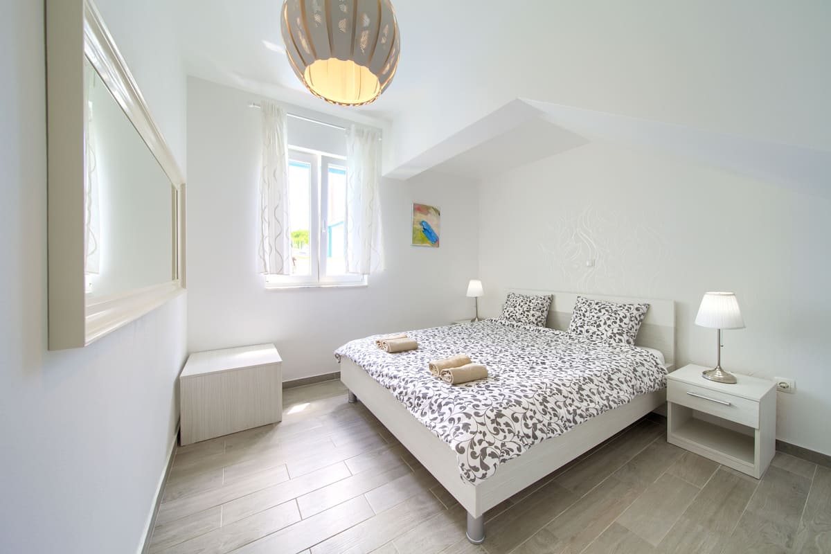 A bedroom with a bed, bedside tables, a window, and a ceiling light.