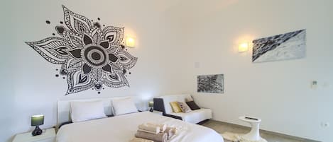 Ein modernes Schlafzimmer mit einem großen Bett, einem Nachttisch mit Lampe, einer Couch mit Kissen und einem Wandbild.