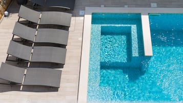 Una piscina al aire libre de temporada, sillones reclinables de piscina