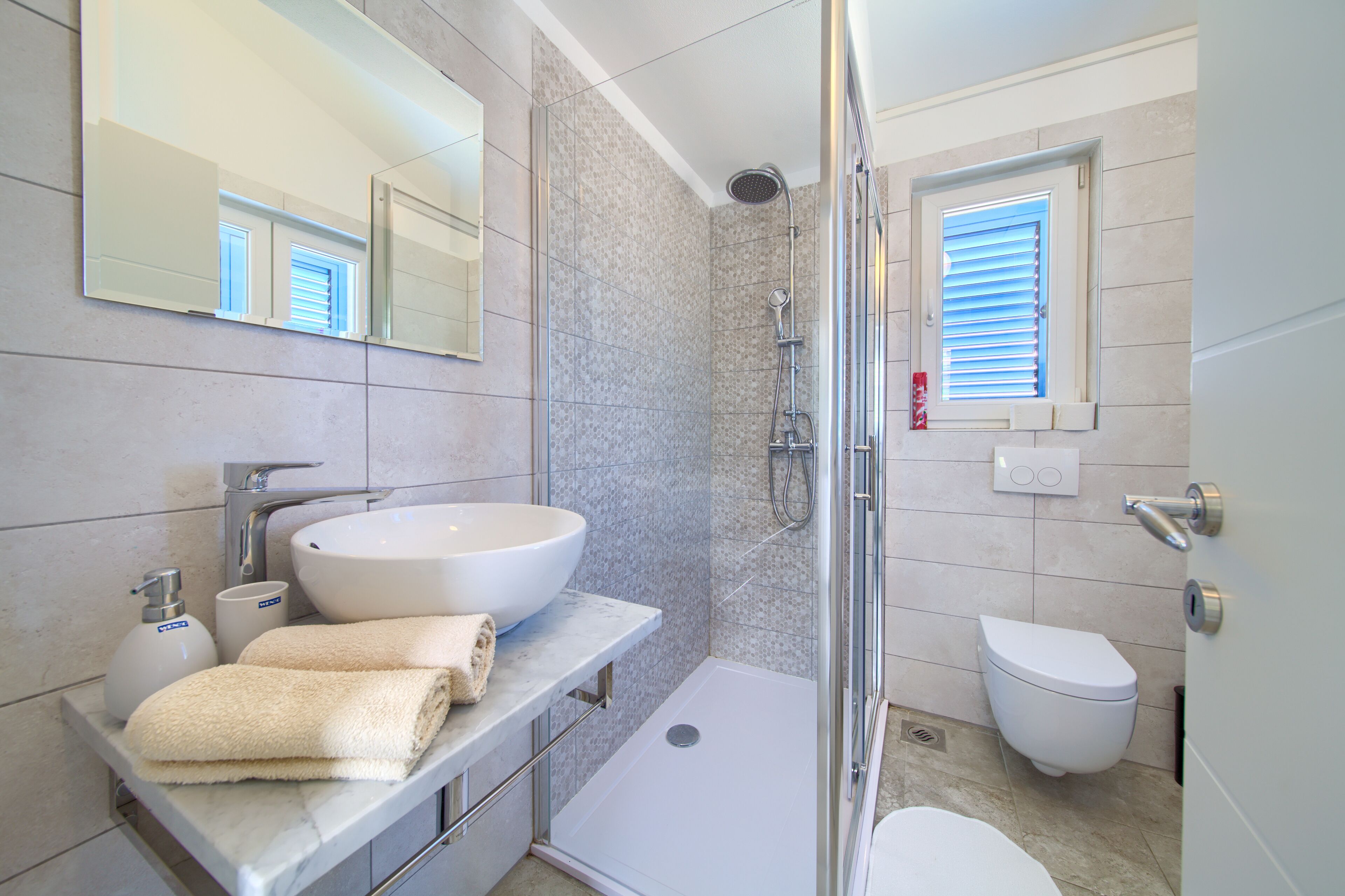 Une salle de bain moderne avec un grand lavabo, un miroir, une douche et des toilettes.