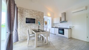 A modern kitchen with white cabinets, a built-in oven, and a stone wall backsplash. - Apartments Mali Nono (Krk)