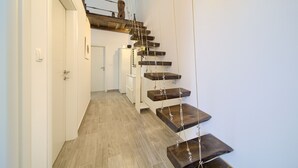 A narrow hallway with a wooden staircase leading to a loft area. - Apartments Mali Nono (Krk)